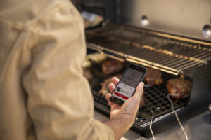 grillzubehör-mann-mit-handyapp-beim-grillen