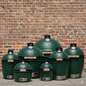 Big Green Egg Familie auf Boden mit Backsteinhintergrund.